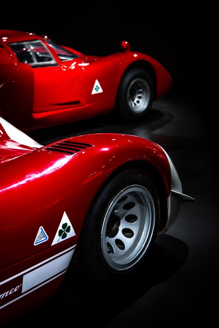Close-up of vintage Alfa Romeo racing cars on display with classic emblems