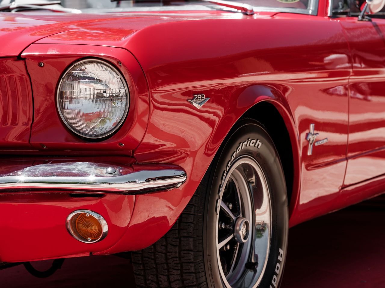 Detailed shot of a classic red vintage car highlighting the front design and headlight.